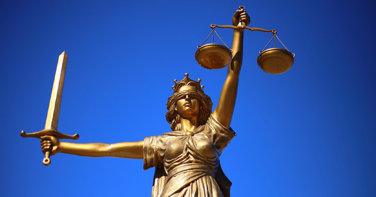 Golden statue of Lady Justice holding scales and sword against blue sky, symbolizing law and fairness